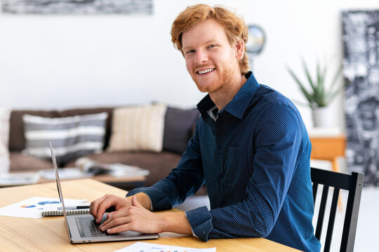 Portrait of confident entrepreneur or small business owner in a modern office or coworking space Successful young businessman is working using laptop sitting workplace Looking at the camera and smile