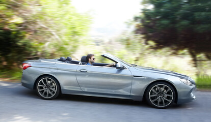 Plakat Feeling the wind in his hair. A young man driving a silver sportscar.
