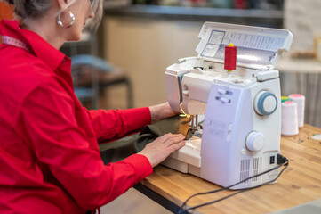 Woman sewing on machine sideways to camera