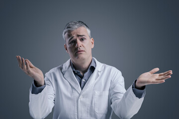 Funny clueless doctor shrugging and looking at camera - obrazy, fototapety, plakaty