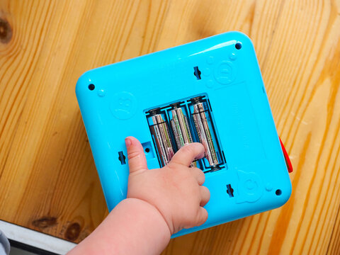 kid baby takes out the batteries from the toy with his fingers