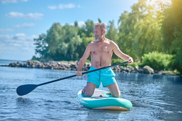 Man with oar on board gliding on water