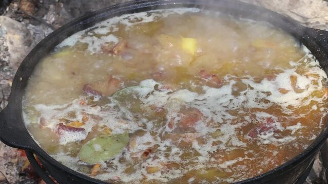 Cooking pilaf or soup outdoors on a campfire. Dishes of the national cuisine of the peoples of the East. Vegetables and meat are cooked in a cauldron.