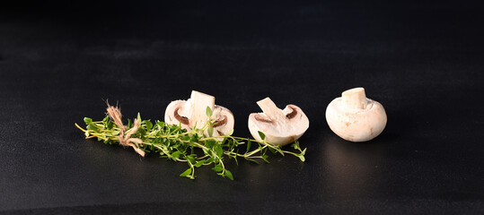Mushrooms champignon with thyme sprig on a dark blue background.