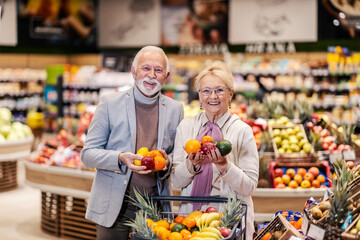 Happy senior couple buying fruits at supermarket.