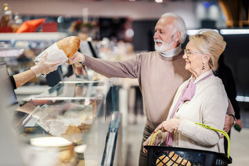 A senior couple buying bread in supermarket.