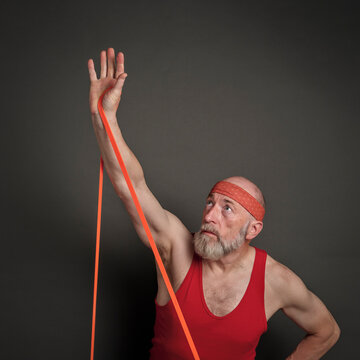 head and shoulder portrait of senior man (in late 60s) exercising with resistance band,  fitness over 60 concept