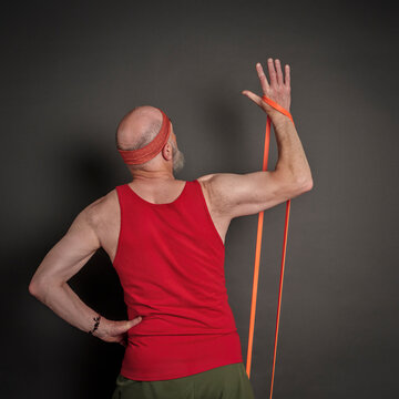 head and shoulder portrait of senior man (in late 60s) exercising with resistance band,  fitness over 60 concept