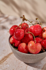 a bowl of ripe cherries on a marble background with a hard light  