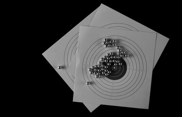 Steel BBs, metal pellets and target isolated on black, top view