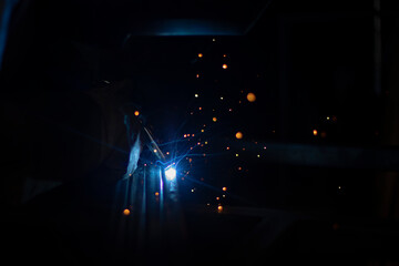 Fire from metal welding. Sparks in the dark when working with a red-hot welding machine. Work with high temperature.