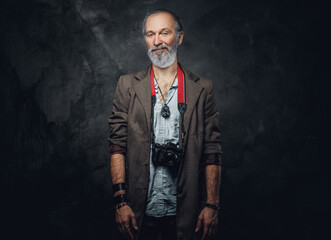 Shot of stylish elderly man photographer with photocamera against dark background.