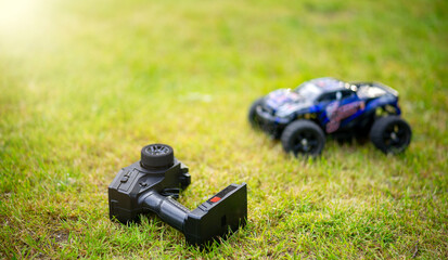 The car is on the control panel.Children's radio-controlled car model on the green grass.A black...