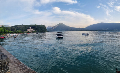 Beach of lake Annecy, boats on water, mountains