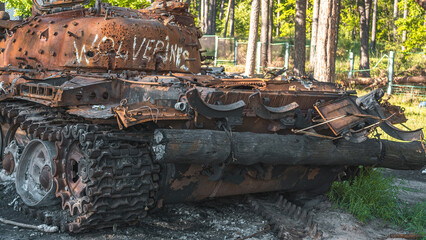 Fototapeta na wymiar War in Ukraine, a destroyed Russian tank with a Ukrainian ensign stands near the road against the backdrop of the forest, rear view
