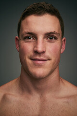 You cant spoil his mood. Studio closeup of a cheerful young man standing against a grey background while looking into the background.