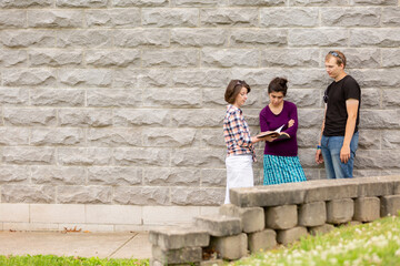 Woman sharing from the Bible with guy and girl