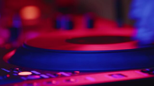 Male DJ's hand rotates round platform and presses buttons on digital mixing console, closeup, side view. Concept of professional musical accompaniment at modern parties in nightclub. Macro