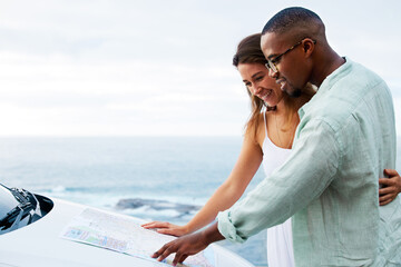 True love never leads you astray. Shot of a happy young couple reading a map on a road trip along...