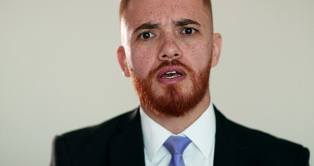 Angry man protesting looking at camera in argument. Upset person wearing business suit talking to camera