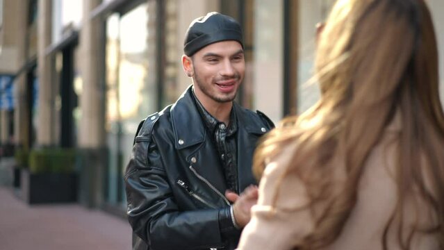 Happy gay man hugging woman on city street talking smiling. Portrait of cheerful Caucasian LGBTQ person meeting friend downtown outdoors on sunny day. Friendship and lifestyle