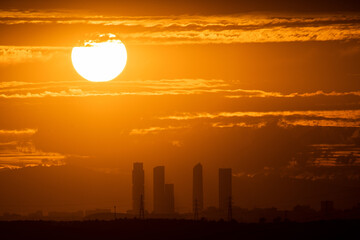 The sun sets during de summer solstice with the view of the skyscrapers and skyline of Madrid.