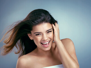 Happy girls are the prettiest. Studio shot of a beautiful young woman laughing against a blue background.