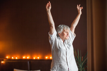 Fototapeta na wymiar Senior woman stretching in bed waking up at home