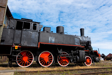 Obraz na płótnie Canvas A steam locomotive standing outside of historic locomotive shed. The shot was taken in natural lighting conditions