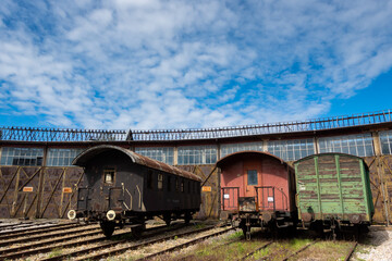 Fototapeta na wymiar Old cargo cars standing outside of historic locomotive shed. The shot was taken in natural lighting conditions ....
