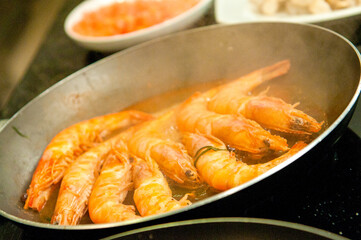 Shrimps being seasoned by the Chef and fried in the frying pan.
