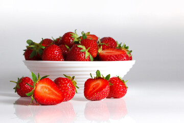 Red ripe strawberry in the white bowl, glossy background