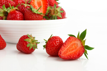 Red ripe strawberry in the white bowl, glossy background