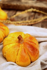 delicious sweet buns in the shape of a pumpkin baked close-up on a wooden surface, pumpkin pastries