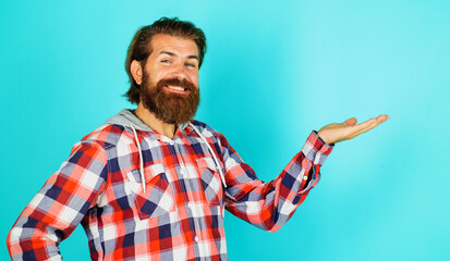Smiling bearded man shows something on palm hand with copy space for product. Advertising. Discount.
