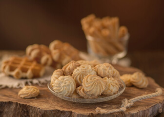 fresh crispy shortbread cookies on a glass plate against the background of Viennese waffles, on a wooden tray, light brown 