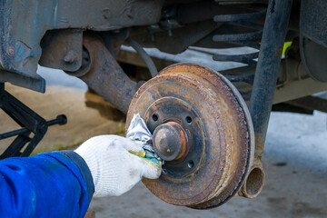 a man cleans a brake disc from rust with a rag