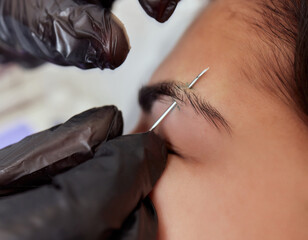 Professional placing the jewel of piercing on the temple on the head with ball. Tragus type.