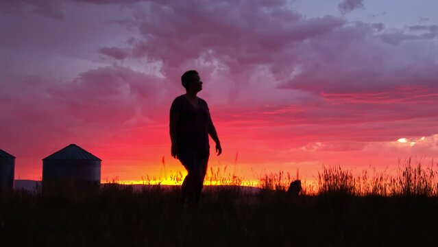 Woman walking in farm field during colorful sunset with vibrant colors in Idaho.