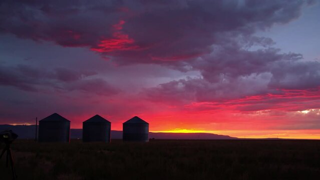 Wide panning view of farm during colorful sunset in Idaho with vibrant colors across the sky.