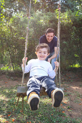 Dad and Son Having Fun on a Swing in the Park. Happy 4 Year Kid Enjoy Swinging.