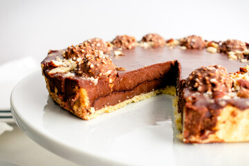 Sliced Chocolate Hazelnut Tart Garnished with Chocolates and Nuts: Chocolate ganache tart garnished with candy and chopped nuts