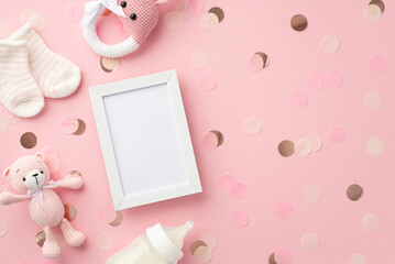 Baby girl concept. Top view photo of photo frame tiny socks knitted bunny rattle toy teddy-bear toy milk bottle and shiny confetti on isolated pastel pink background with blank space