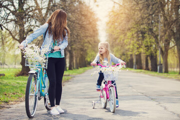 mother and child riding bikes in park