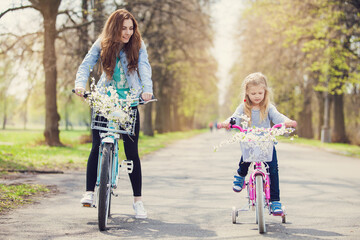 mother and child riding bikes in park