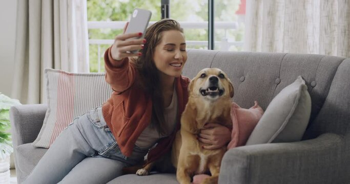 Happy young woman taking a selfie with her dog on the couch at her house. Caucasian woman with her puppy. Fun and relaxing day on the couch with your pet and phone. Love and kiss human and animal.