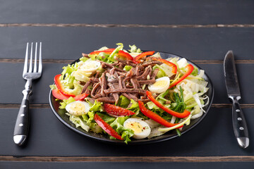 Beef tongue and fresh vegetables on a plate served with fork and knife. Beef tongue salad