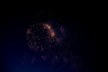 Bright orange fireworks and lots of blue and purple sparks on the background of the night sky. High...