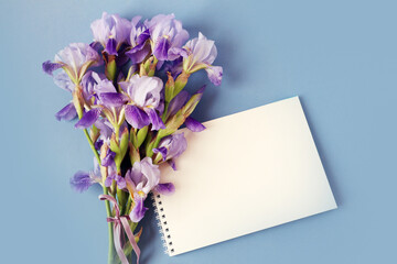  Greeting card: a bouquet of blue irises in a notebook on a blue background, top view, space for text