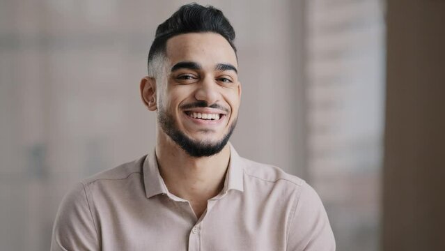 Portrait of confident calm young man arabic ethnic male handsome brunet guy turn head at camera happy male human bearded face positive smiling hispanic millennial businessman shows toothy health smile